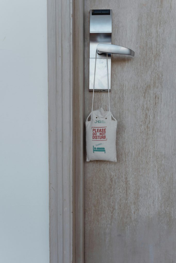 Close-up of a hotel room door with a do not disturb sign hanging on the handle.